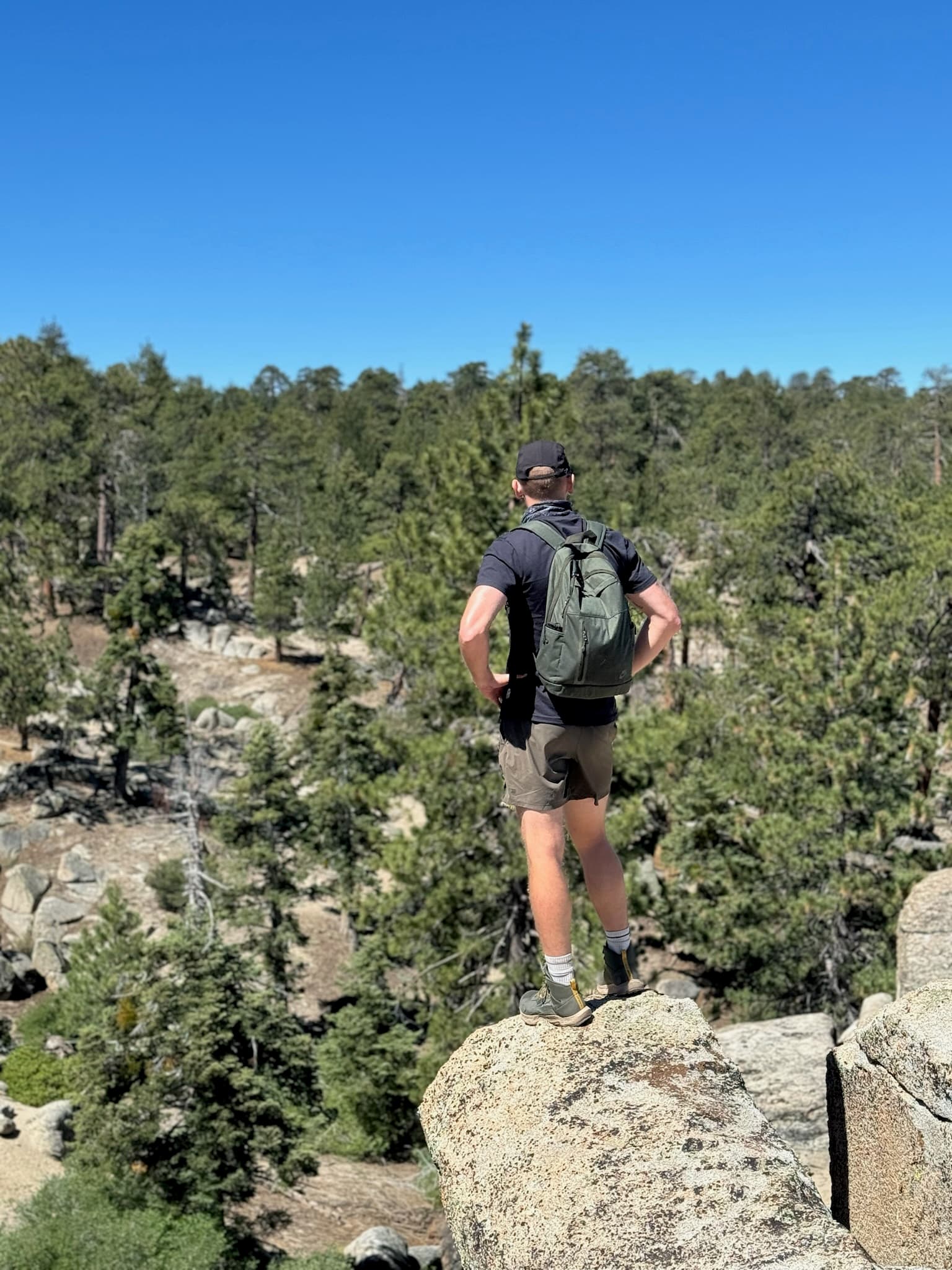 A hiker standing on a rock ledge, looking out over a scenic landscape